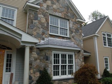 Two-story home with extensive stone siding and a porch.
