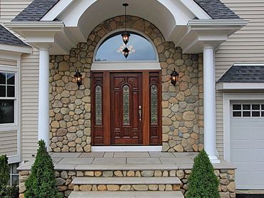 Stone veneer around a curved entrance with a dark wood door.
