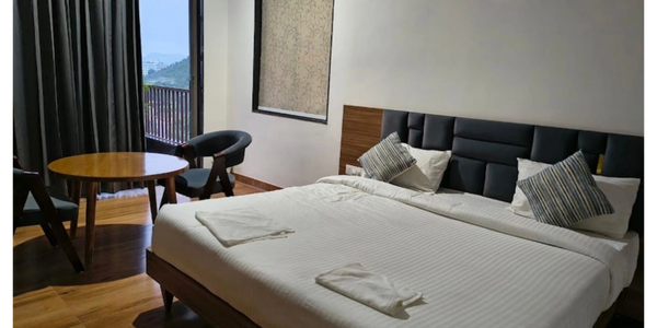 Modern hotel room with a large bed and seating area.