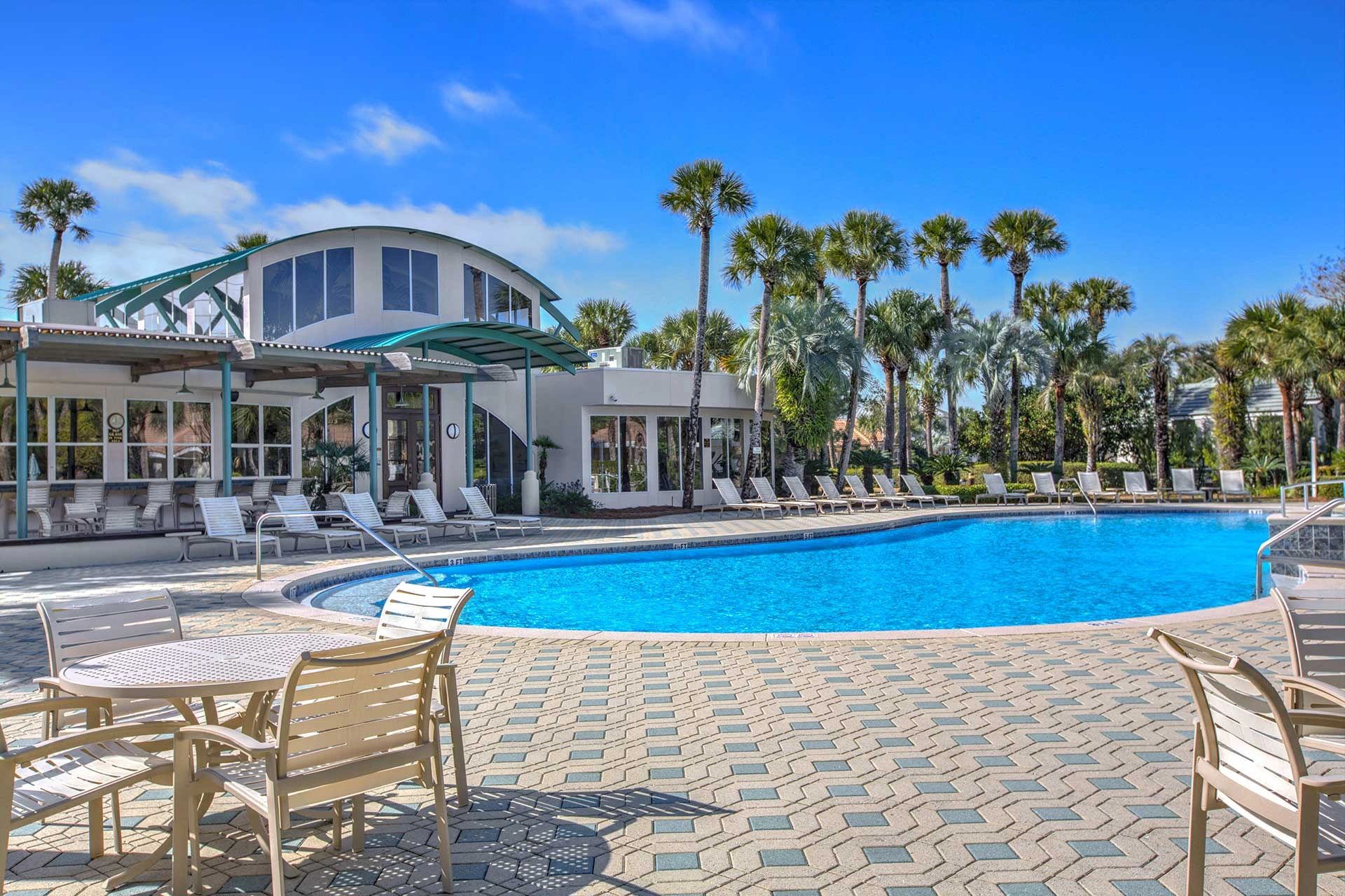 Outdoor swimming pool with palm trees and seating area.