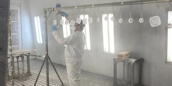 Person spray painting objects in a workshop.