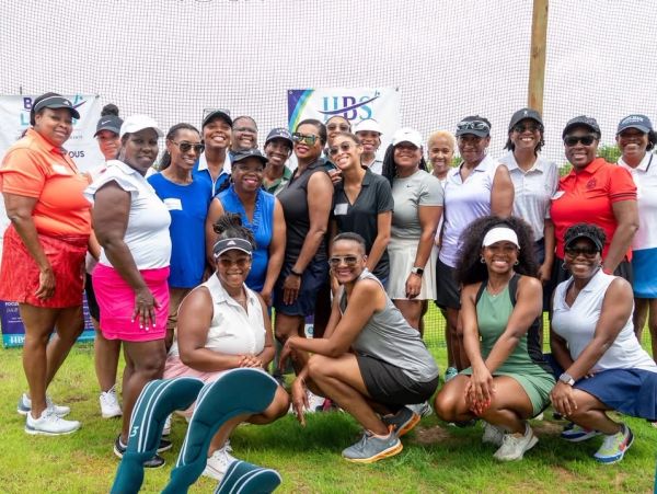 Group of women golfers posing together on a grassy field.