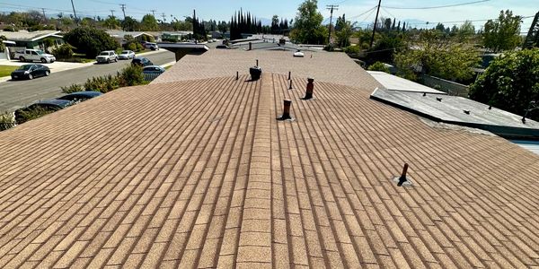 Long brown tiled roof with vents and pipes.