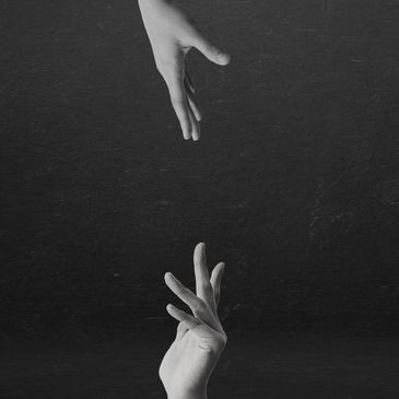 Two hands reaching towards each other against a dark background.