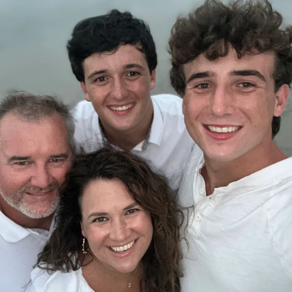 A happy family of four smiling together outdoors.