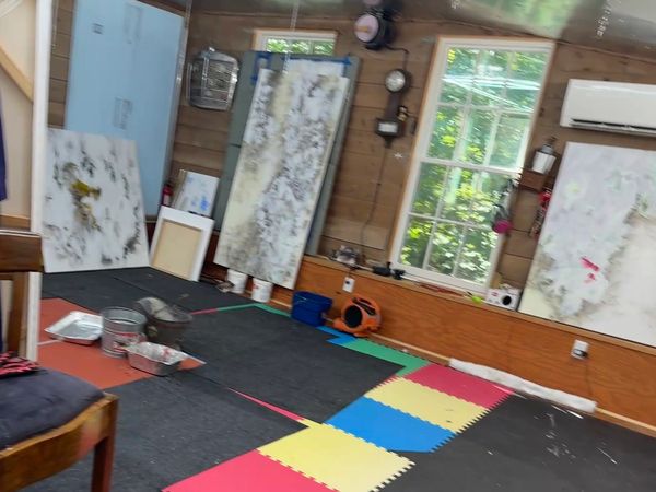 Art studio with paintings and colorful floor mats.