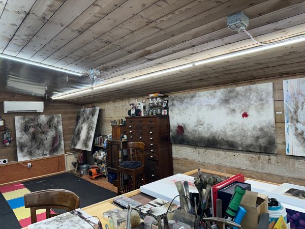 Art studio with wooden walls and abstract paintings.