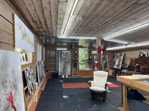 Art studio with paintings and comfy chair.