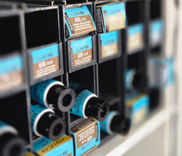 Close-up of organized hair dye bottles in a salon storage rack.