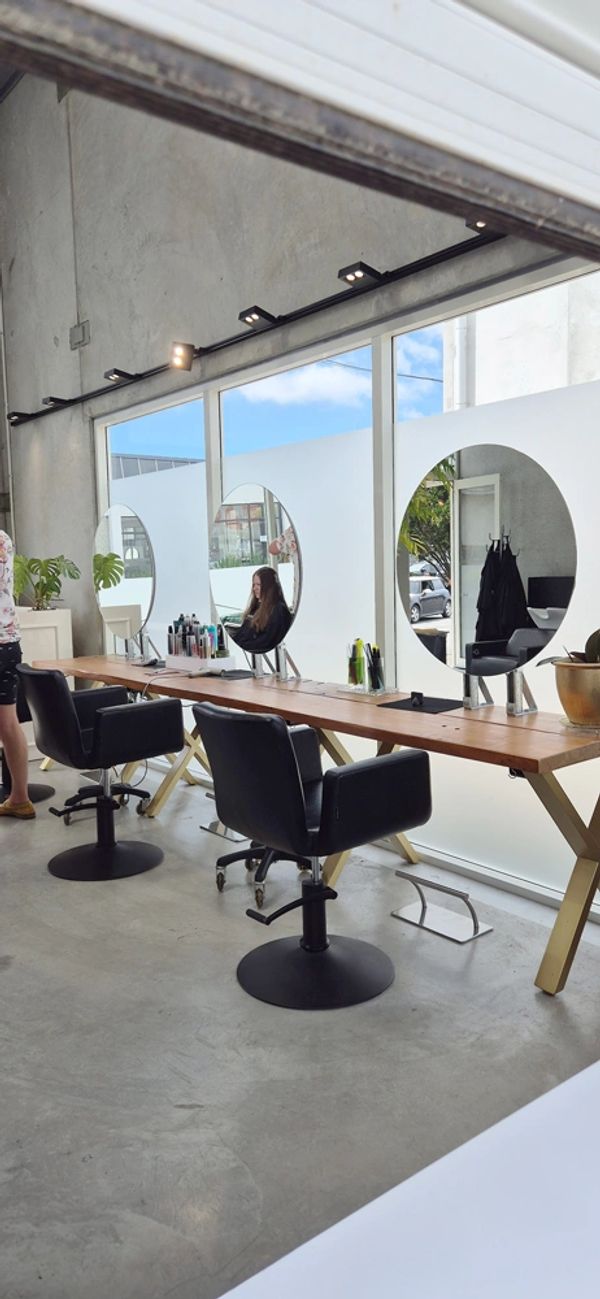 Modern hair salon with black styling chairs and circular mirrors.