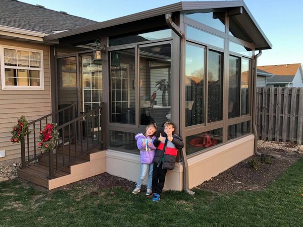 Children standing in front of earthstone (brown) all season sunroom. 