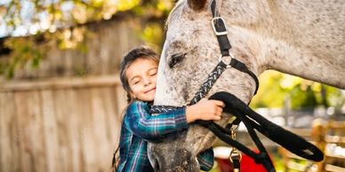 Child lovingly hugging the head of a horse