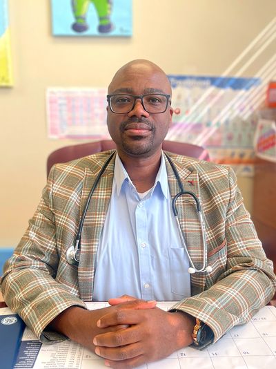  A picture of the doctor sitting with his hands crossed, in his office.