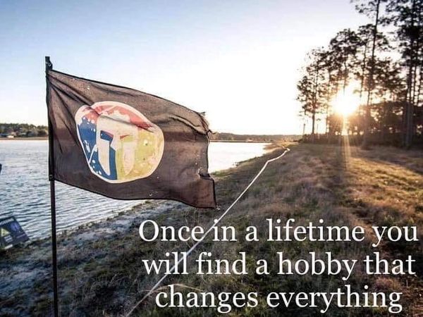 Flag by a lake with a motivational hobby quote at sunset.