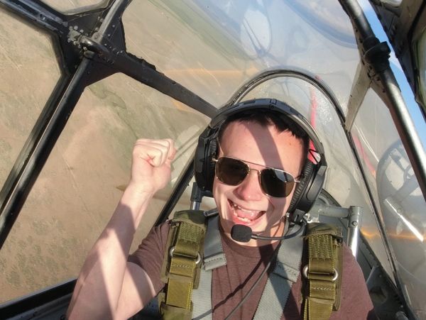 Excited pilot inside a small aircraft cockpit, celebrating mid-flight.