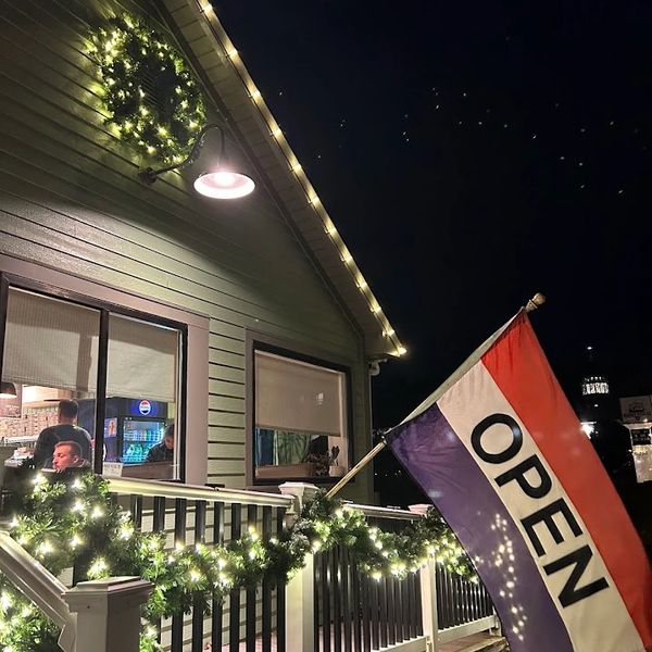 Cozy building decorated with lights and an open sign flag at night.