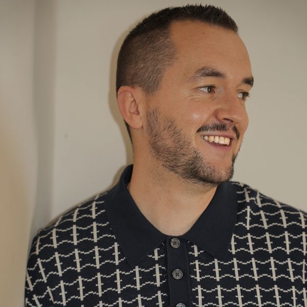 Smiling man with short hair and beard, wearing a patterned polo shirt.