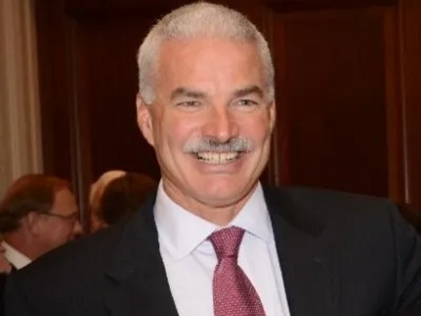 Smiling man in a suit and tie at an indoor event.