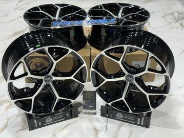 Set of glossy black and silver car rims displayed on a marble floor.