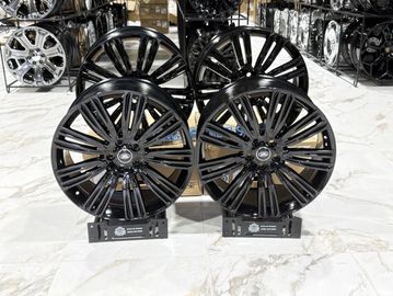 Two black alloy car wheels on display stands in a showroom.