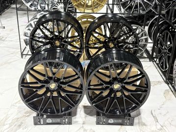 Four black stylish car rims displayed on a showroom floor.