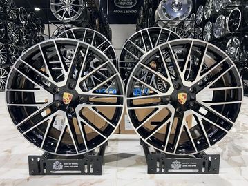 Two stylish Porsche alloy wheels displayed in a showroom.