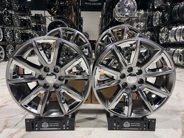 Set of four shiny silver alloy car wheels displayed in a showroom.