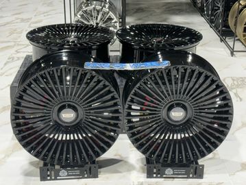 Two sets of shiny black multi-spoke car rims on display.