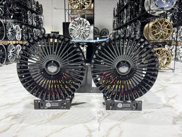 Two black turbine-style car rims displayed indoors.