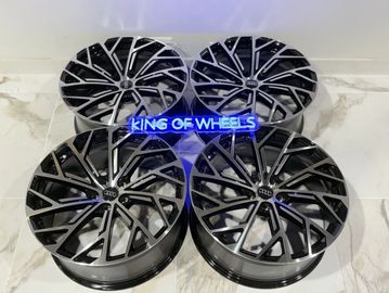 Four black Audi alloy wheels displayed on a marble floor.