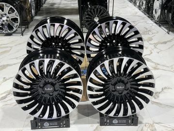 Set of four black and chrome alloy car wheels displayed indoors.