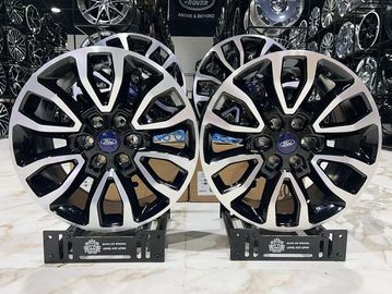 Two black and silver Ford alloy wheels on display stands.