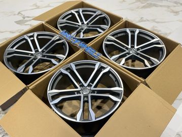 Set of four black and silver car rims in cardboard boxes.