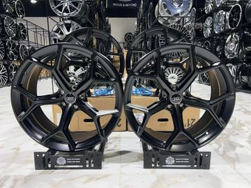 Two black Audi alloy wheels displayed on stands in a showroom.