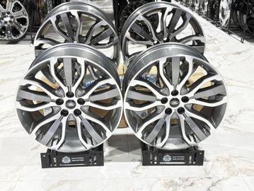 Set of four shiny alloy car wheels on display stands.
