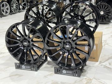 Four black alloy wheels displayed on stands inside a showroom.