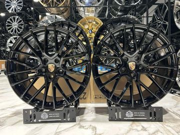 Two black Porsche alloy wheels displayed on stands.