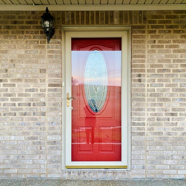 Red front door on residential brick house 