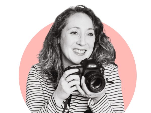 Smiling woman holding a Canon EOS camera with a pink circle background.