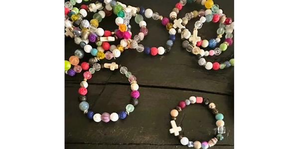 Colorful beaded bracelets with cross charms on a dark wooden surface.
