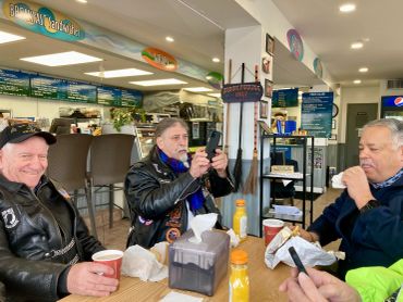 Three men enjoying a meal at a casual cafe.