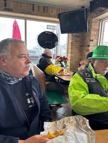 Two men sitting in a restaurant, one wearing a green hat.