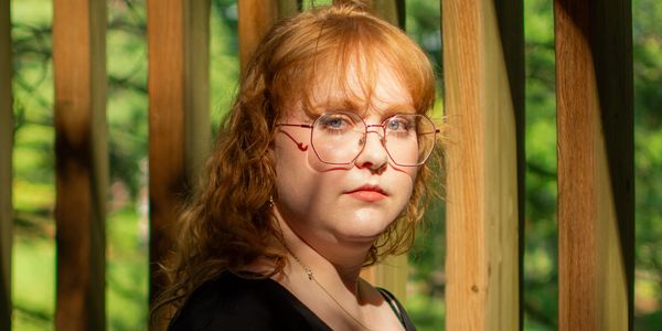 Young woman with glasses outdoors in sunlight.