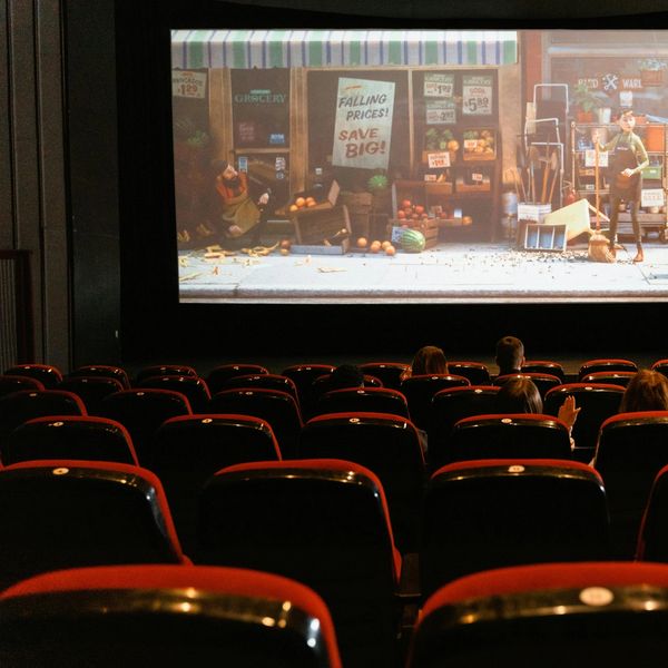 Audience watching a screening for an animated movie in a vintage theater with red seats.