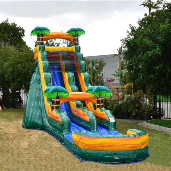 Colorful inflatable water slide with tropical palm tree decorations set outdoors.