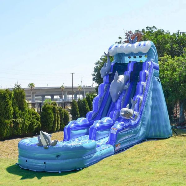 Large blue inflatable water slide with dolphin decorations on a grassy lawn.