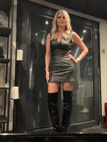 Woman in black leather dress and thigh-high boots.