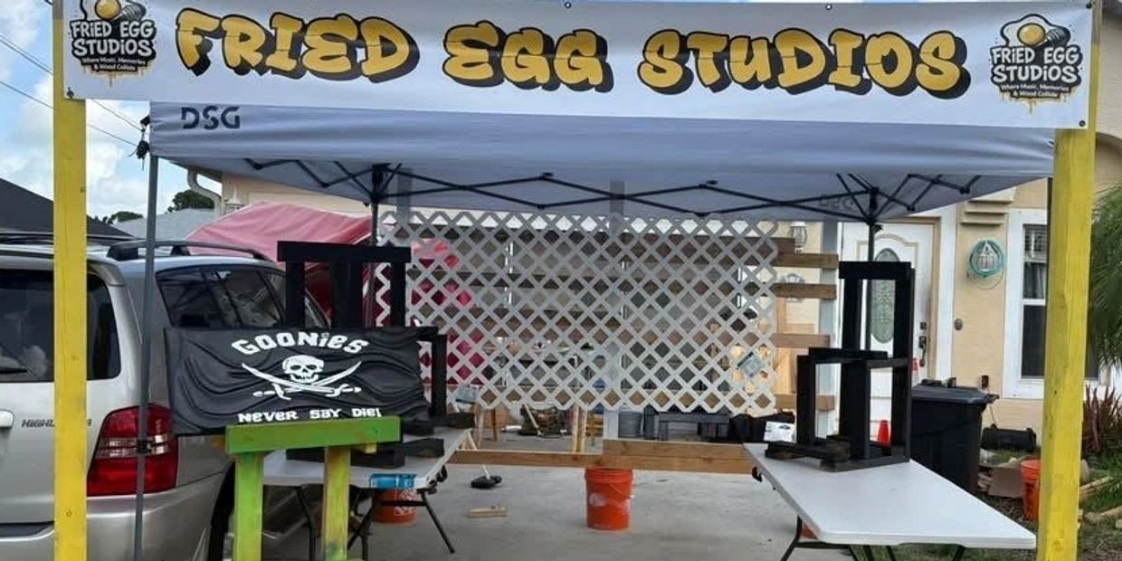 Outdoor booth for Fried Egg Studios with a Goonies-themed sign and black wooden displays.