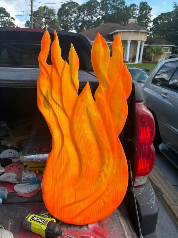 Bright orange wooden flame shape resting on a truck bed.