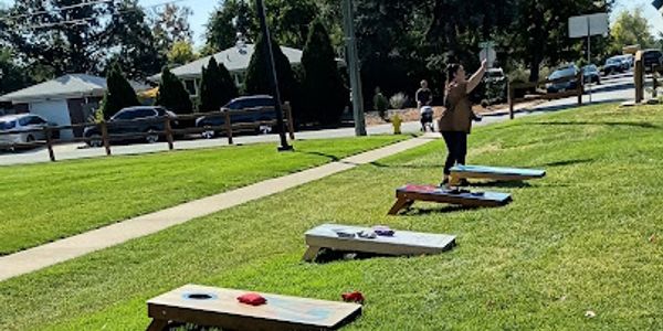 People playing cornhole on a sunny day in a park.